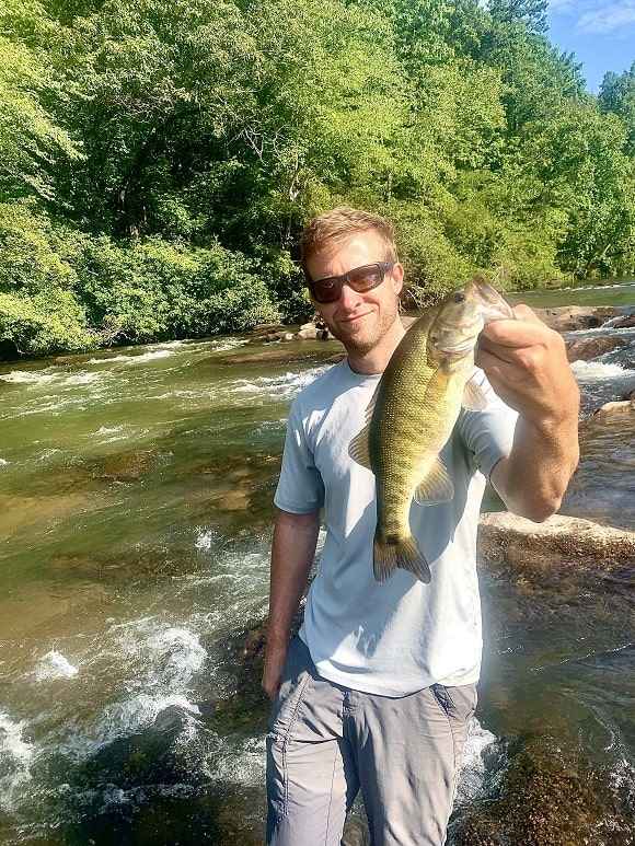 a fly fisherman with a shoal bass from the chattahoochee river