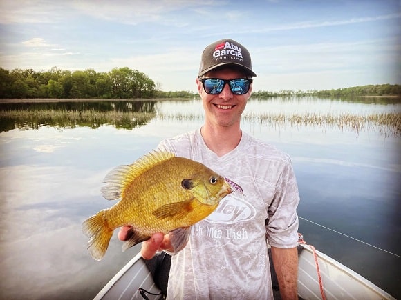 a happy angler on his boat holding a big clear water bluegill
