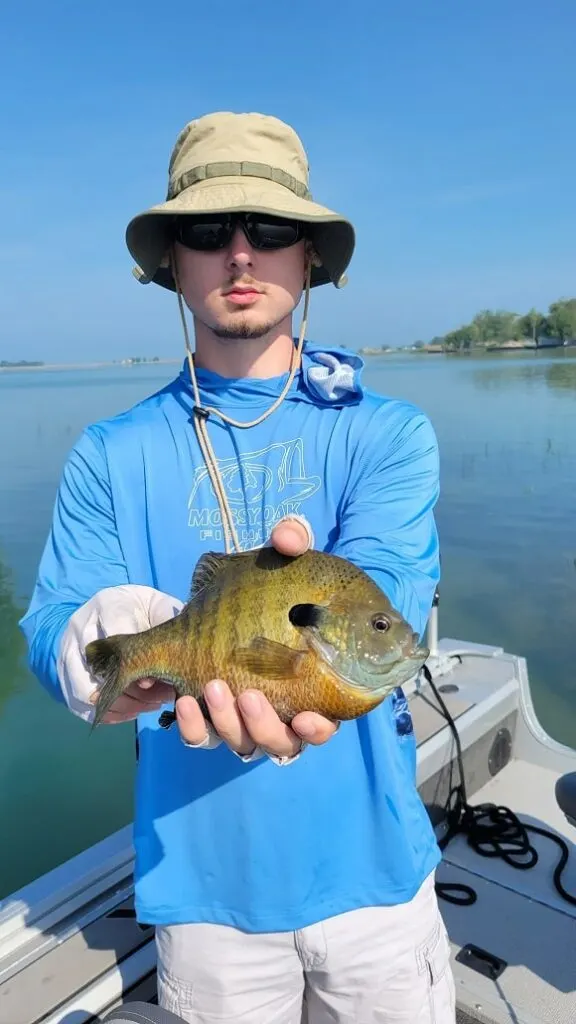 a young angler on his boat with a very nice summer bluegill