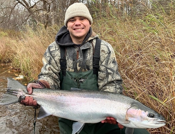 a happy angler from New York holding a gigantic winter steelhead