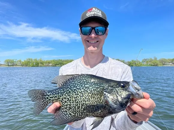 a US angler on his boat holding a big crappie that he has landed with the Ego reach landing net