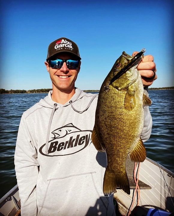 a happy angler on his boat with a really big clear water smallmouth bass