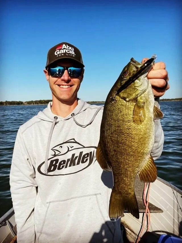a happy angler on his boat with a really big clear water smallmouth bass