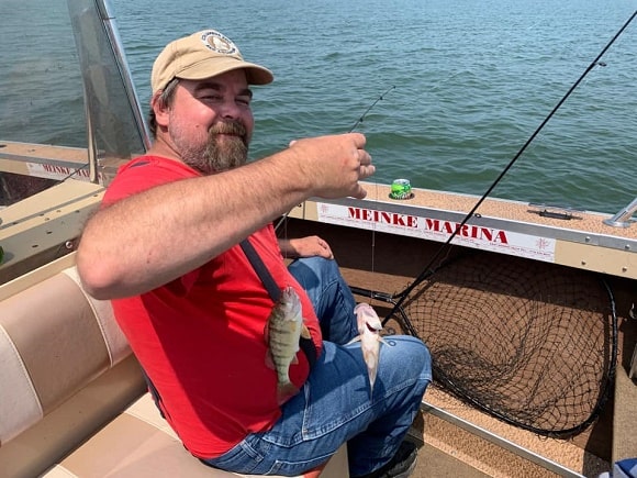 a happy angler on a boat with a pari of small yellow perch