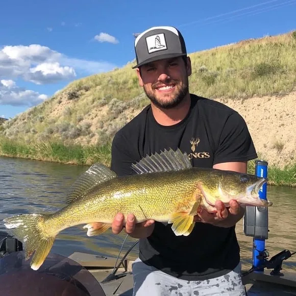a happy angler on a lake holding a very big walleye