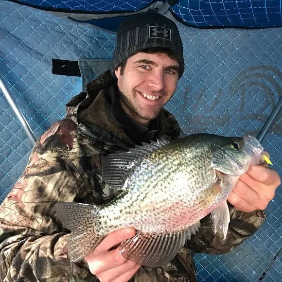 an ice angler in his shelter fishing for winter crappie
