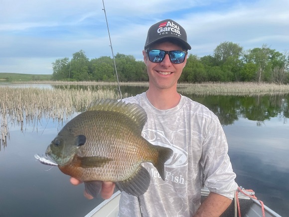 a happy panfish angler on his boat holding a giant bluegill caught with an fc leader