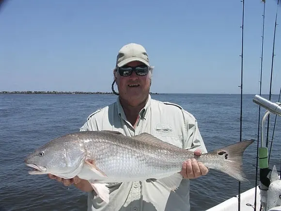 a fisherman on the ocean with a smaller red fish