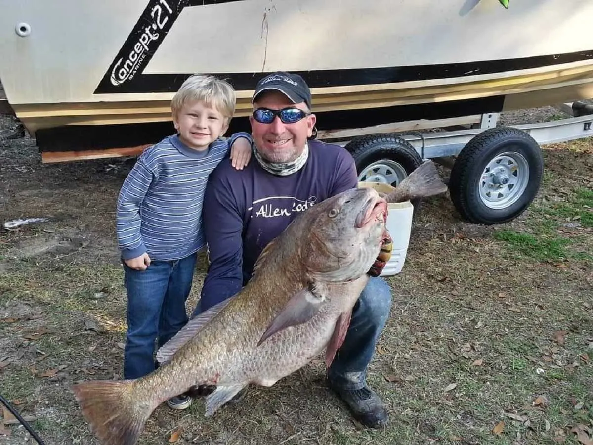 a proud father and his son with a giant black drum