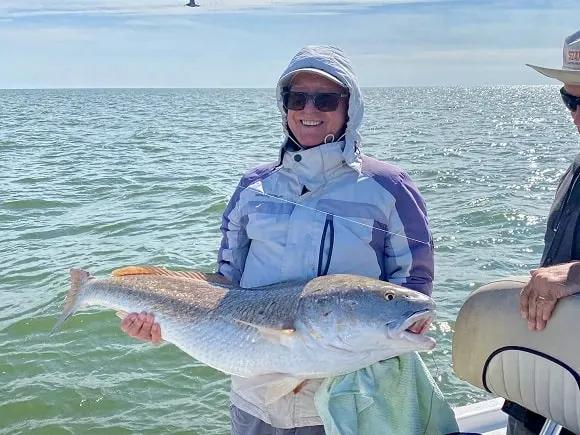 a saltwater angler on a boat holding a heavy black drum