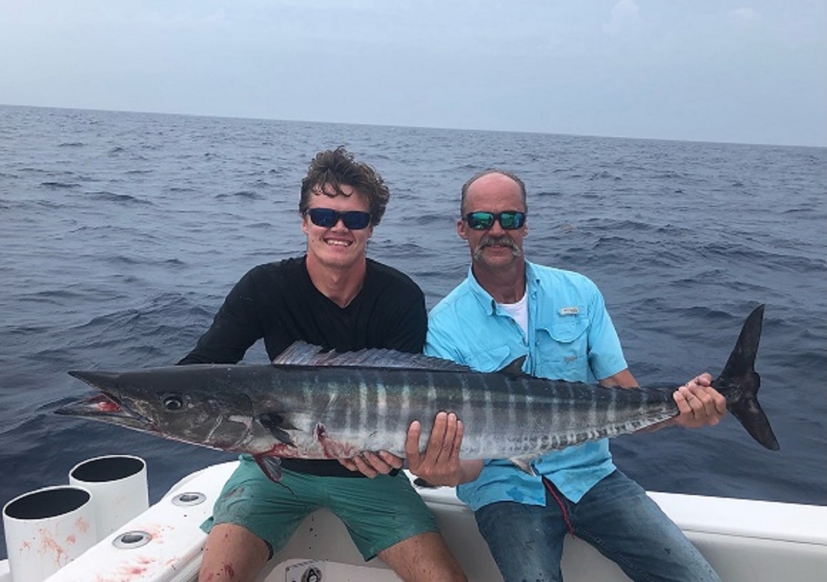two saltwater anglers holding a giant wahoo