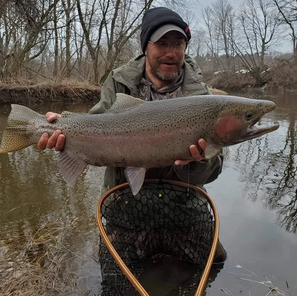 a happy trout angler holding a very big river steelhead