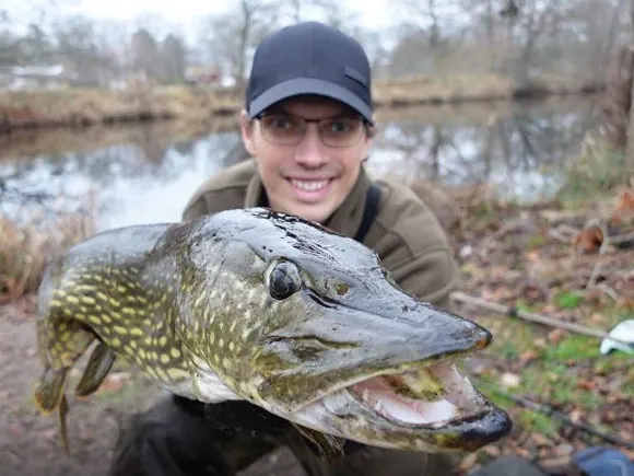 a happy angler holding a big northern pike