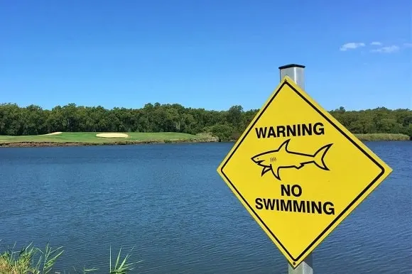 a shark warning sign on a golf course in Australia